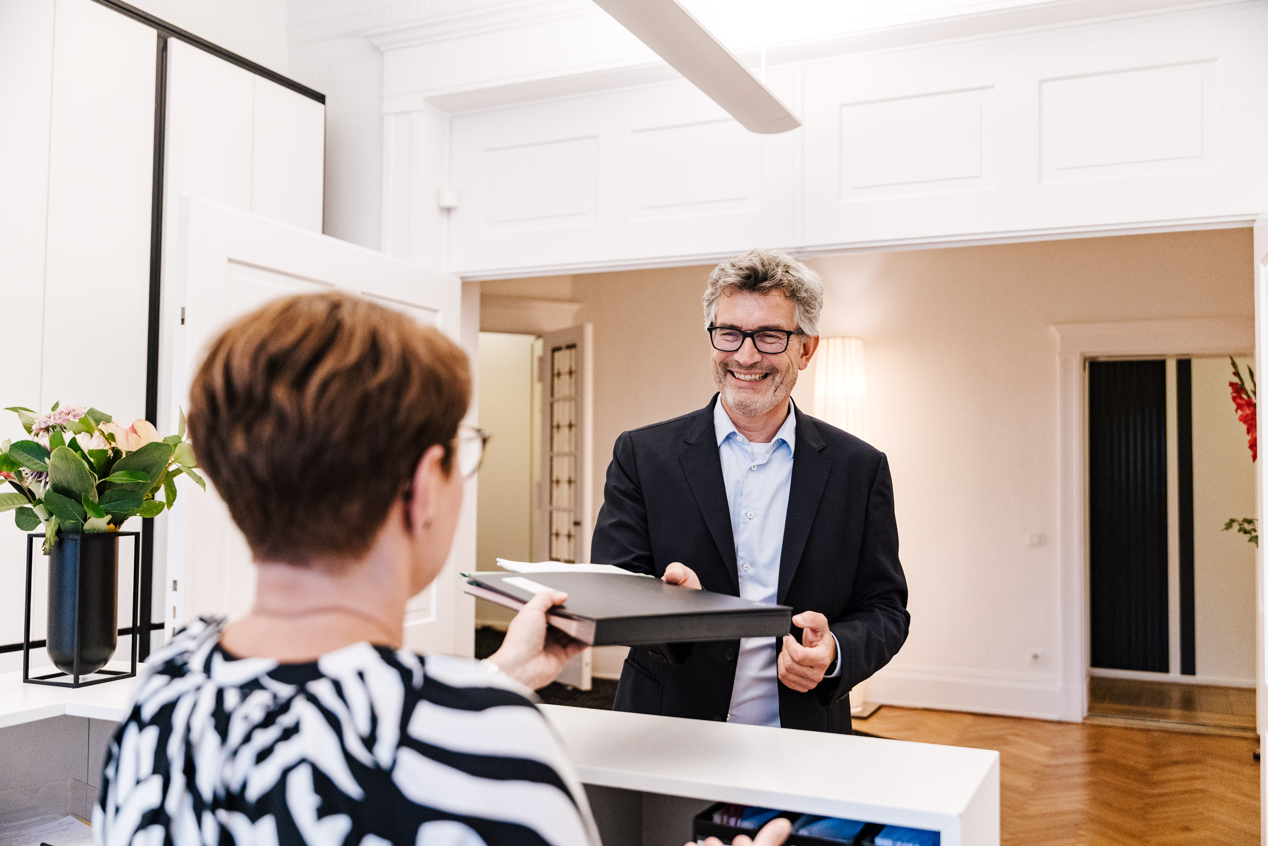 Notar Gutsche übergibt Dokumente an die Kollegin am Empfang.